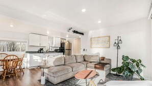 Un salon moderne comprenant un canapé, une table basse et un coin repas avec des chaises.