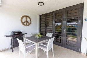 Un patio con mesa y sillas, una parrilla y un ventanal corredera.