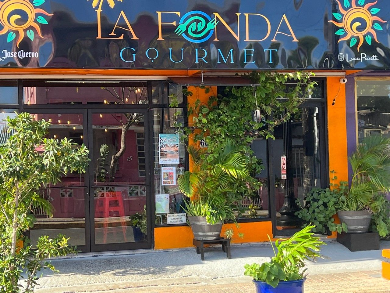 Una fachada con el nombre 'LA FONDA GOURMET' y un logotipo de un sol con una hoja.