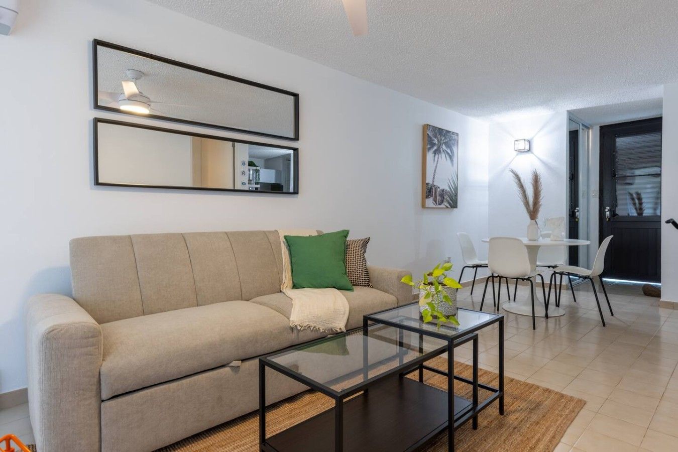 Una sala de estar moderna con un sofá, una mesa de centro de vidrio y un comedor con sillas.