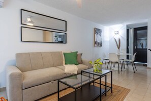 Una sala de estar moderna con un sofá, una mesa de centro de vidrio y un comedor con sillas.