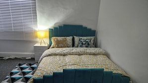 Une chambre à coucher avec un lit, une table de chevet, une lampe et un tapis à motifs géom étriques.