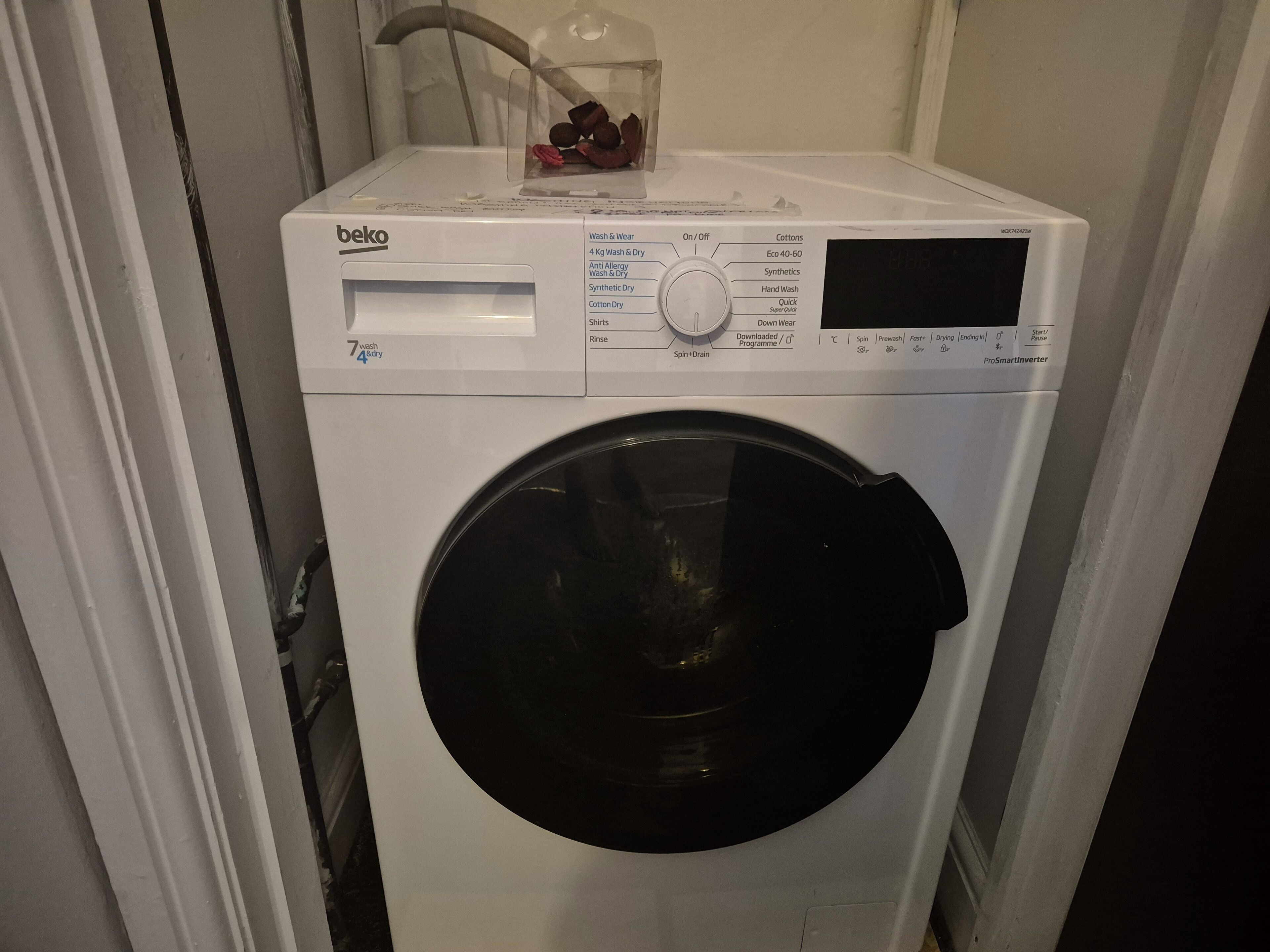A front-loading washing machine with a control panel, a transparent detergent container, and a black drum.