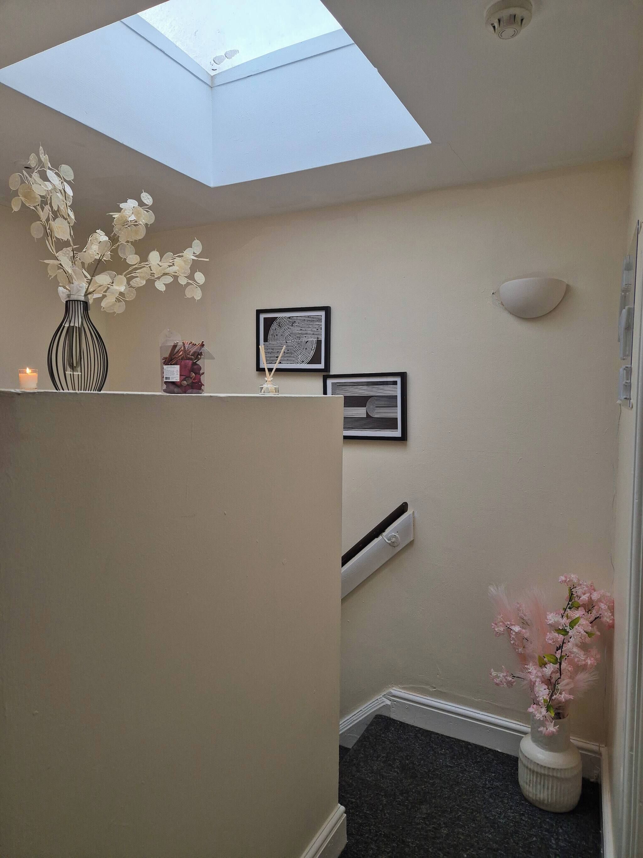A room with a skylight, a small shelf with decorative items, and a wall-mounted air conditioner.