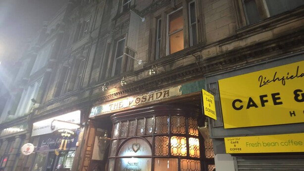 Une vue de rue nocturne avec un bâtiment sur lequel on peut voir une enseigne de café.