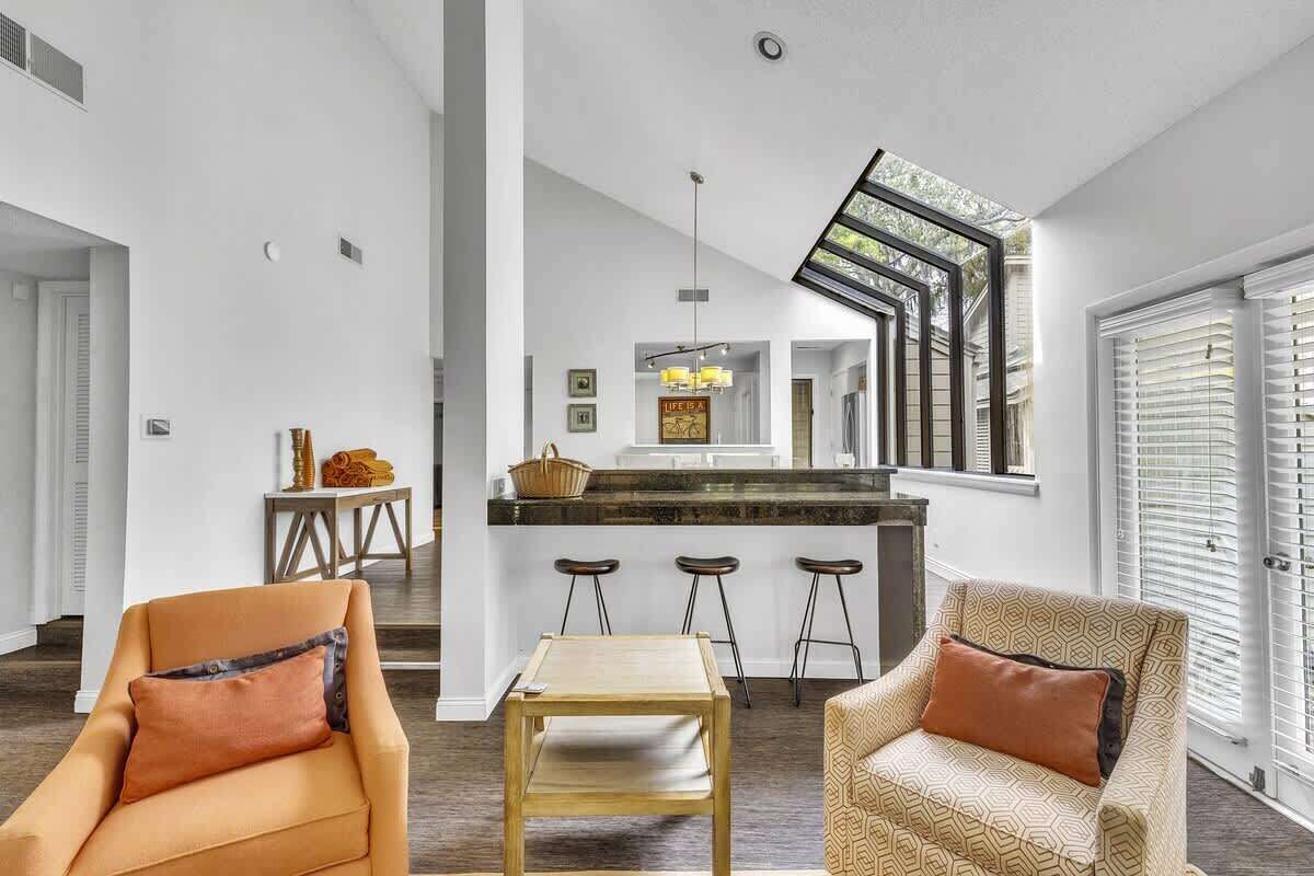 A modern interior with a kitchen island, bar stools, and a staircase leading to an upper level.