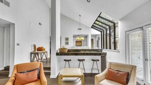 Un intérieur moderne avec un îlot de cuisine, des tabourets de bar et un escalier menant à un niveau supérieur.