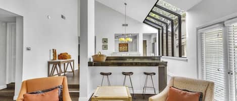A modern interior with a kitchen island, bar stools, and a staircase leading to an upper level.