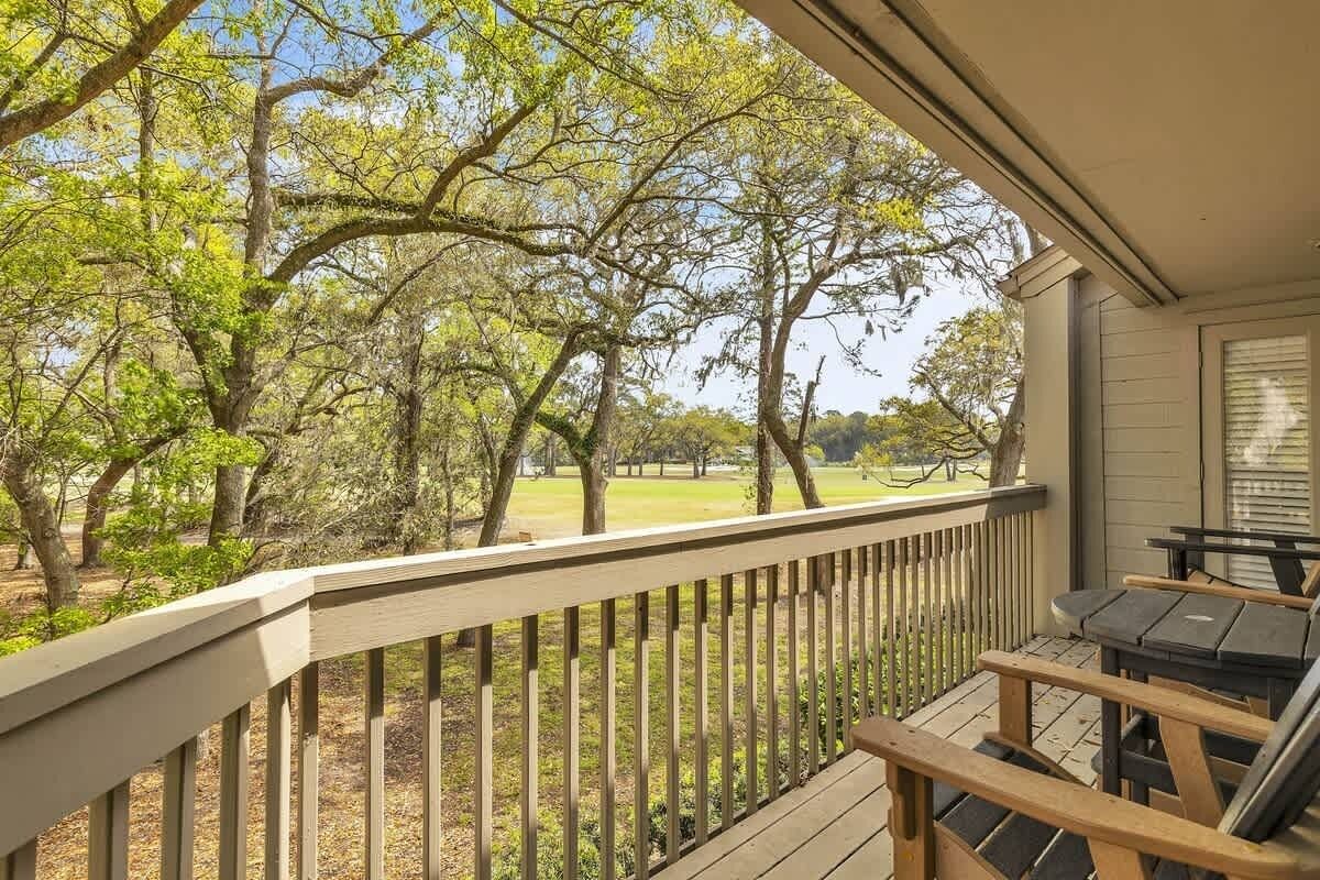 A wooden deck with a railing, a table, and chairs.