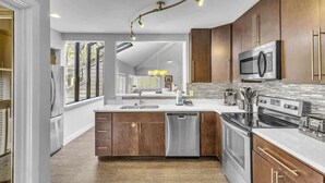 Une cuisine moderne avec des meubles en bois, des appareils en acier inoxydable et un grand îlot central.