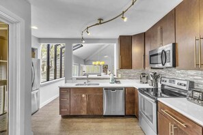 A modern kitchen with wooden cabinets, stainless steel appliances, and a large island.