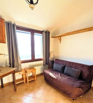 Cozy living space with a sofa, dining table, and chair, perfect for relaxing or working.