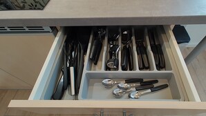 Eine Schublade mit verschiedenen Küchenutensilien, darunter Messer, Löffel und ein Pfannenwender.