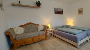 Ein gemütliches Schlafzimmer mit einer Holzsofa, einem Bett mit blauer Bettwäsche, einem Nachttisch mit Lampe und Wandregalen mit Pflanzen und Kunstwerken.