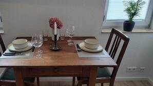 Ein Esstisch, gedeckt mit Tellern, Besteck und Weingläsern, mit Stühlen an beiden Seiten.