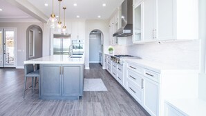 Una cocina moderna con una isla central, armarios blancos y piso gris.