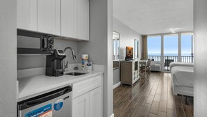 Una cocina moderna con armarios blancos, una cafetera y vistas al balcón.