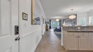 A modern kitchen with a granite countertop, beige cabinetry, and a chandelier.