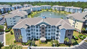 A multi-story residential building with a central courtyard and a small pond.