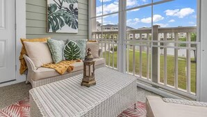 A cozy room with a sofa, cushions, a lantern, and a view of a fenced outdoor area.