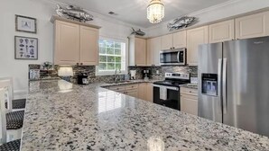 A modern kitchen with granite countertops, stainless steel appliances, and decorative fish on the cabinets.