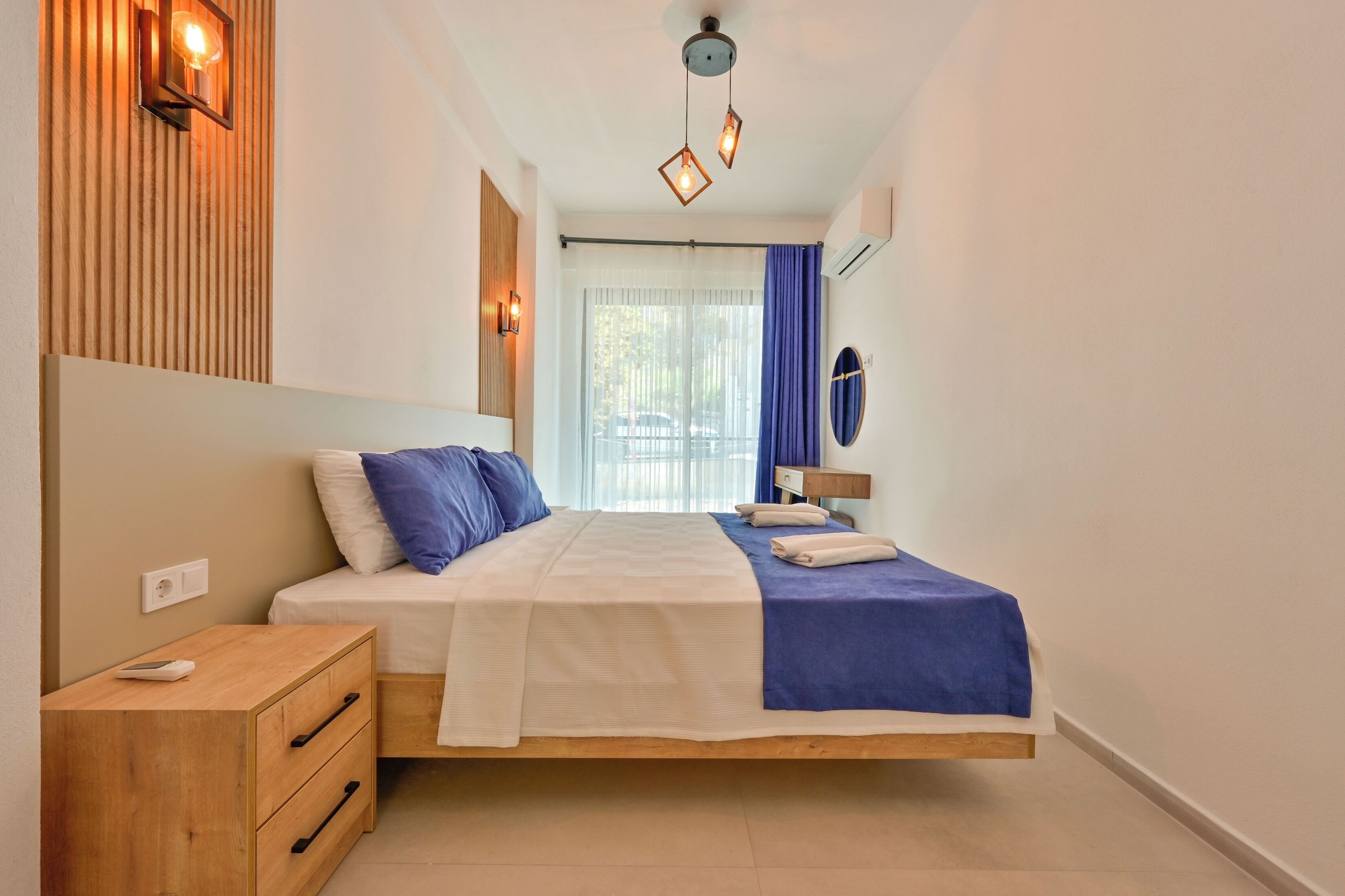 Um quarto moderno com cama, mesa de cabeceira e luminária na parede.