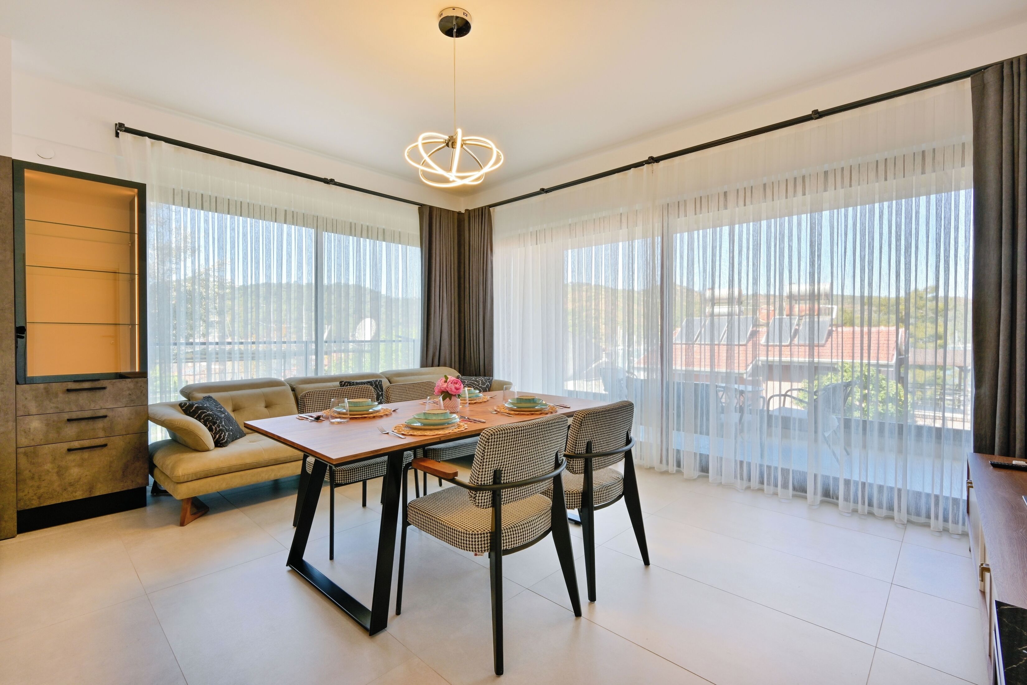 A modern dining area with a table set for four, surrounded by chairs, and a sofa.