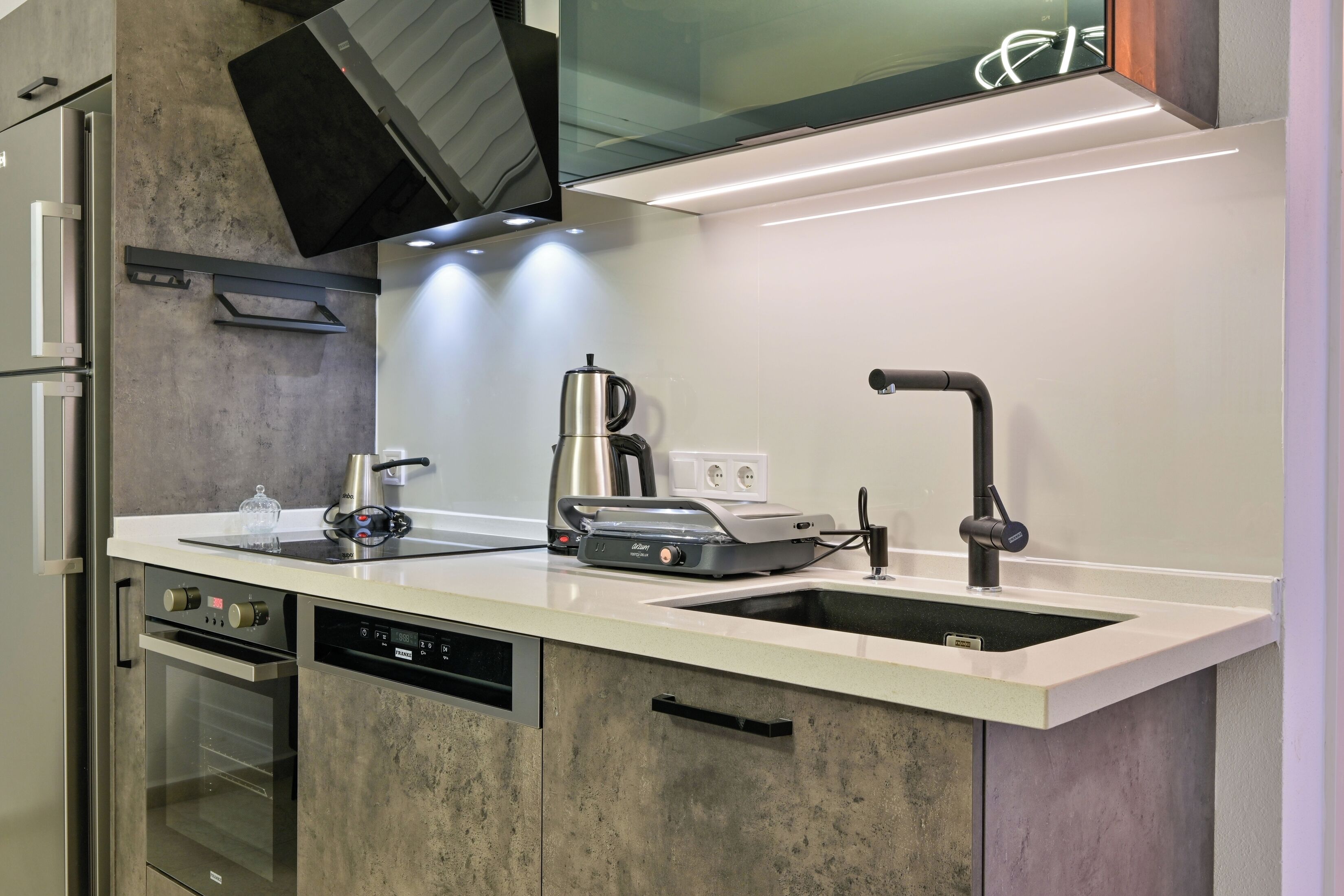 Una cocina moderna con horno empotrado, cafetera y fregadero.
