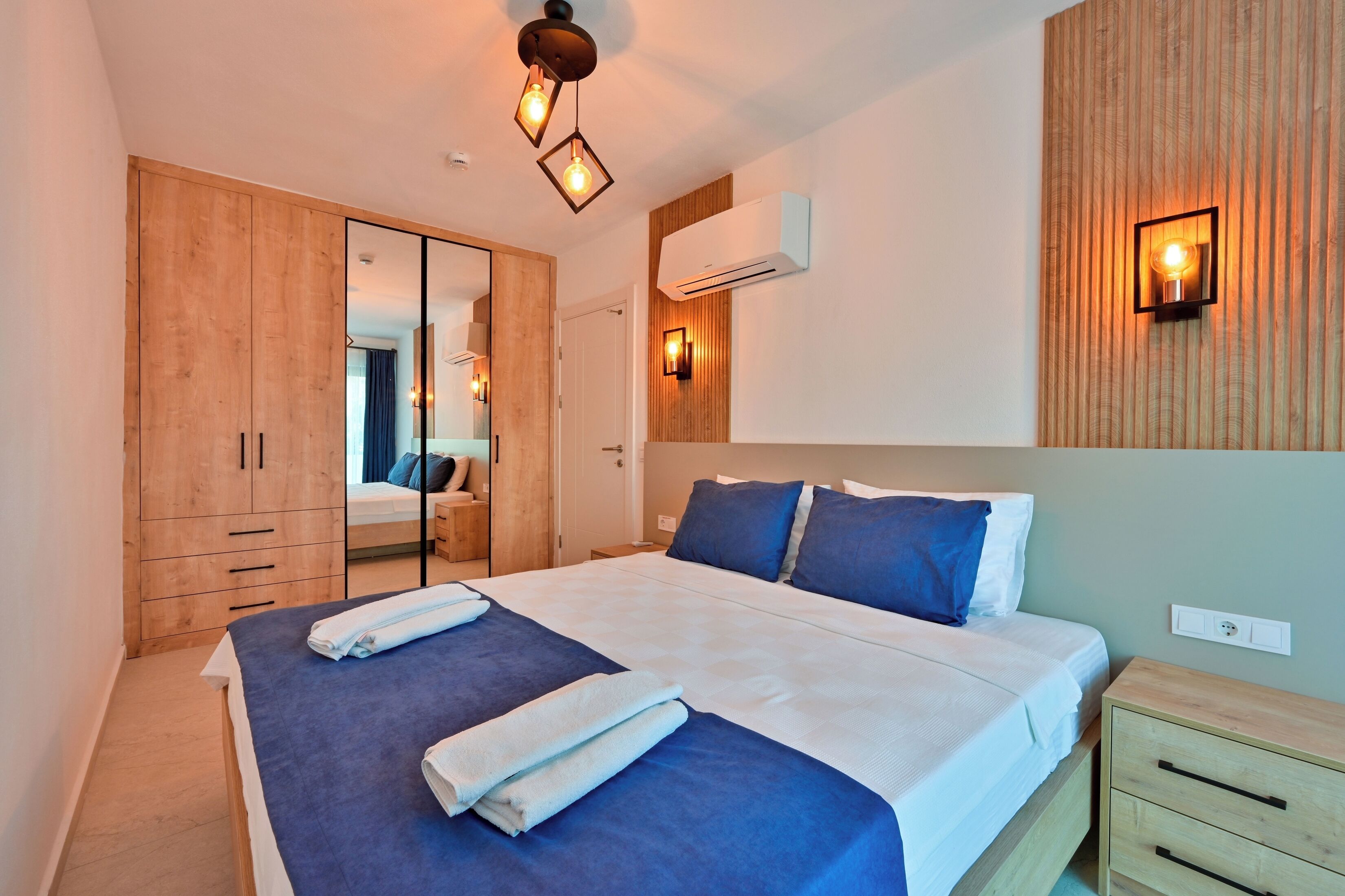 Un dormitorio moderno con una cama grande, un armario de madera y un espejo.