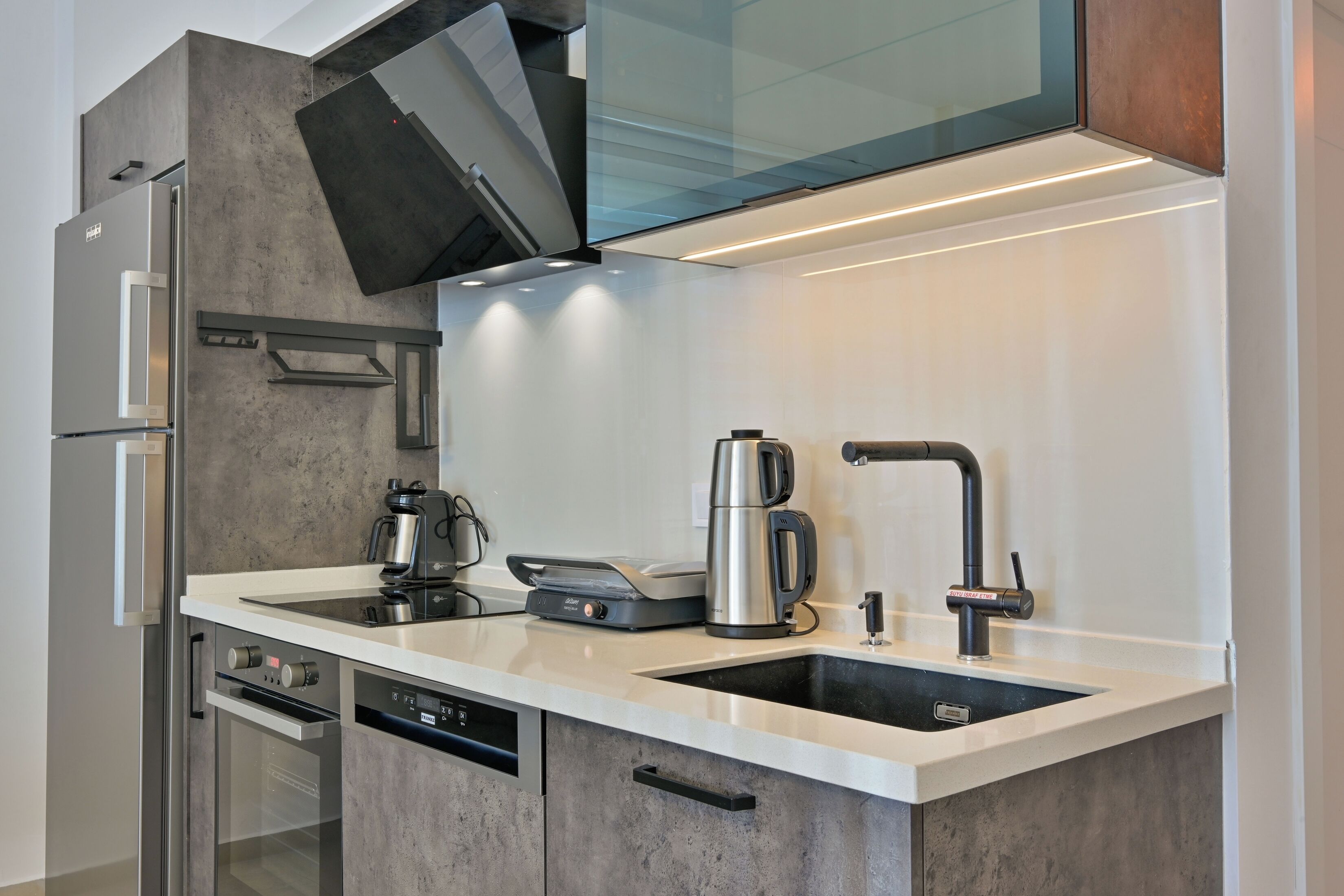 Una cocina moderna con horno empotrado, cafetera y pileta.