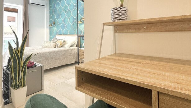 Un dormitorio con cama, mesita de noche y una planta en maceta.