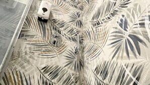 Un baño con un espejo grande, una ducha de diseño moderno y un suelo estampado.