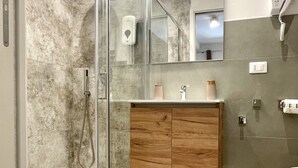 Un baño moderno con cabina de ducha de vidrio, tocador de madera y un inodoro.
