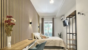 Un dormitorio moderno con cama, mesita de noche y televisor montado en la pared.