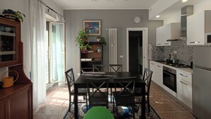 A modern kitchen with a dining area, featuring a large table, chairs, and a hanging light fixture.