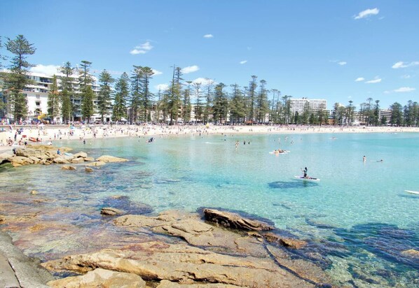 Enjoy the serene beach scene with turquoise waters and rocky formations, perfect for swimming and paddleboarding.