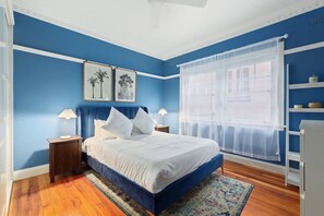 Cozy retreat with a white bed, bedside tables, and a window with sheer curtains.
