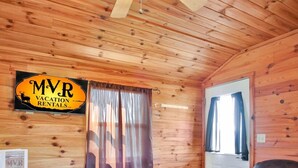 Ein Interieur einer Holzhütte mit einem Esstisch, einer Couch und einem Schild für MVR Vacation Rentals.