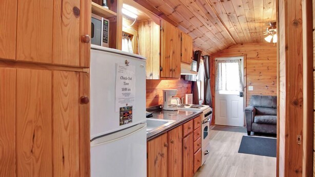 Ein Holzblockhaus-Innenraum mit Küche, Essbereich und einer Couch.
