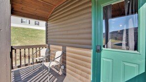 Ein überdachter Balkon mit Holzboden, einer grünen Tür und zwei Stühlen.