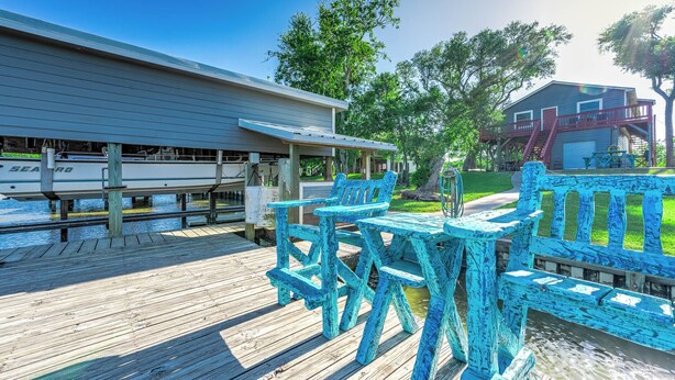 Une terrasse en bois dotée d’un espace salon couvert et d’un quai pour bateaux.