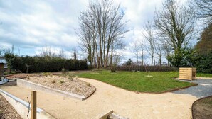 A landscaped garden with a gravel path, a grassy area, and a wooden structure.