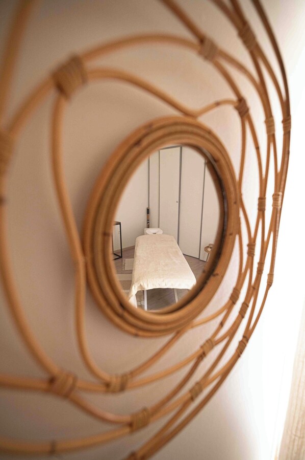 A circular mirror with a reflection of a room featuring a bed and a standing lamp.