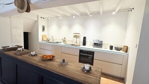 A modern kitchen with a wooden countertop, a built-in oven, and a coffee machine.