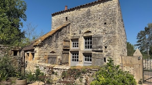 A stone building with a rustic appearance, featuring a mix of stone and wooden elements, including a chimney and multiple windows.