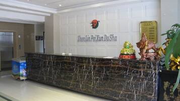 A reception desk with a marble top, a logo above it, and a plaque to the right.