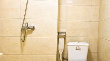 A bathroom with a toilet, a shower, and a wall-mounted toilet paper holder.