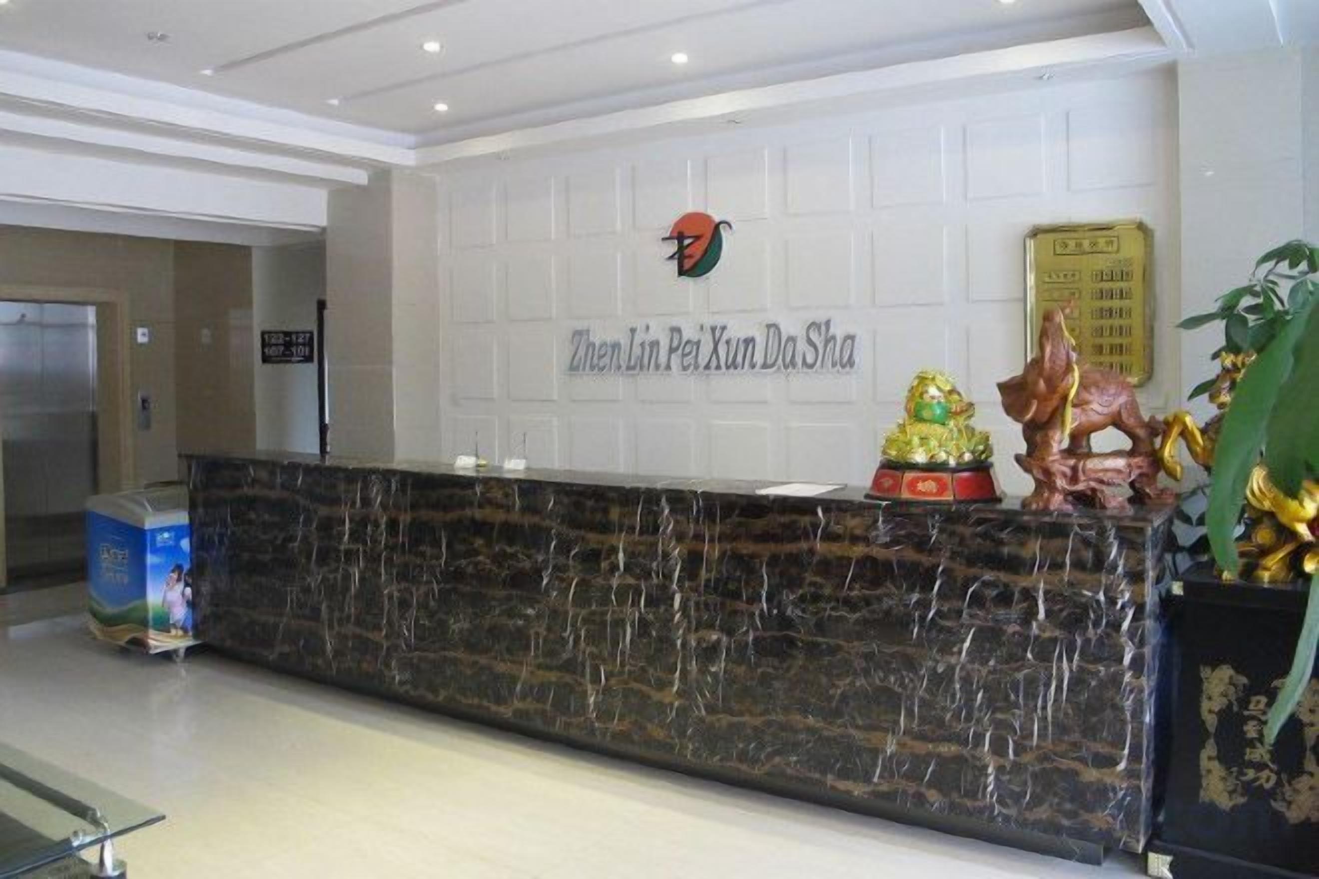 A reception desk with a marble top, a wall-mounted sign, and decorative statues.