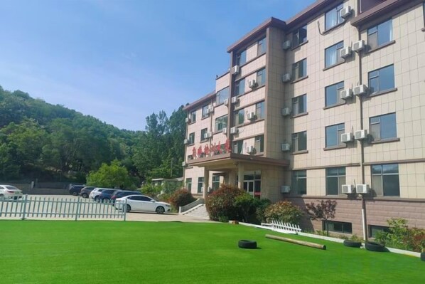 Un edificio de varios pisos con techo plano, estacionamiento y césped bien cuidado.