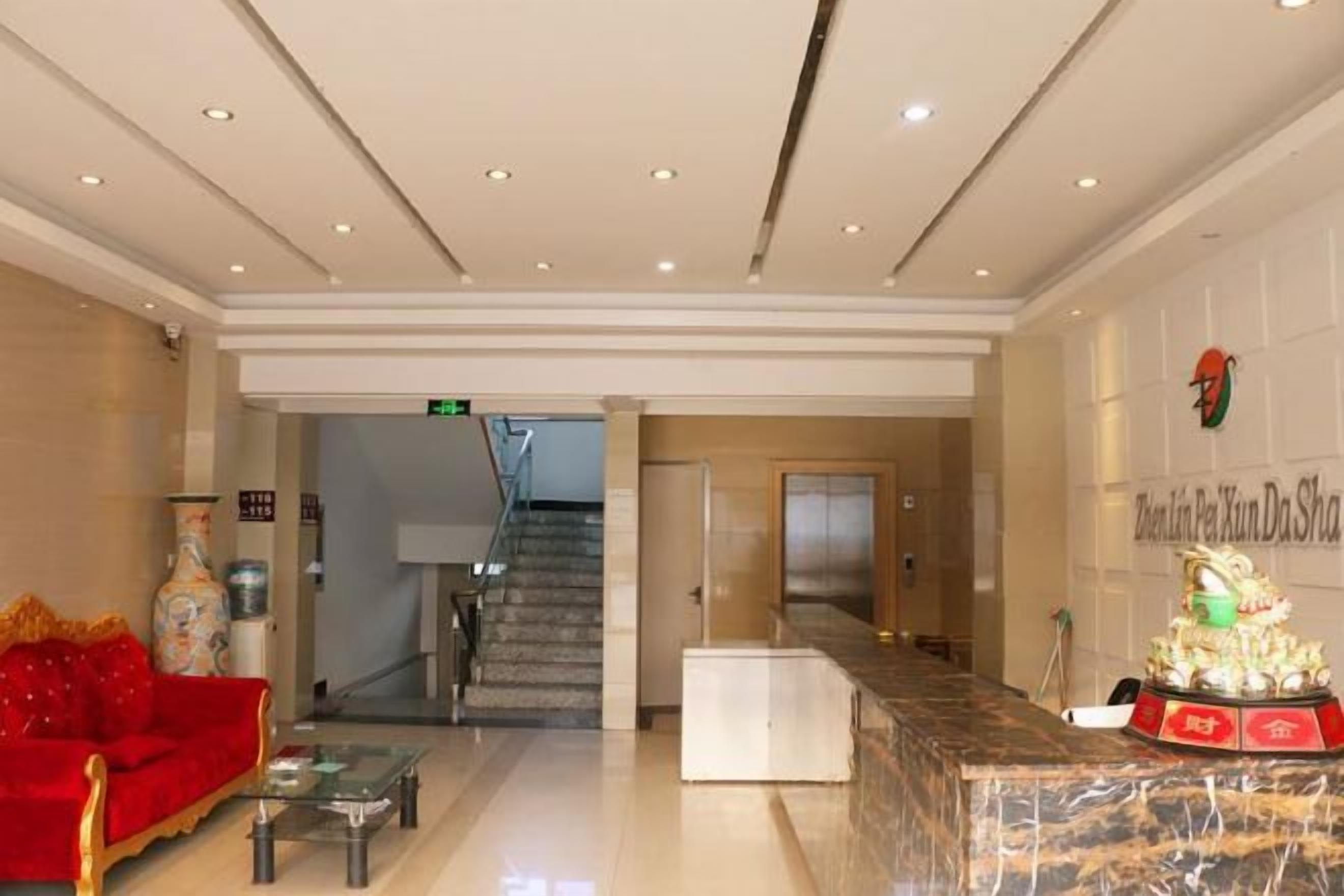 A hotel lobby with a reception desk, a staircase, and a red sofa.